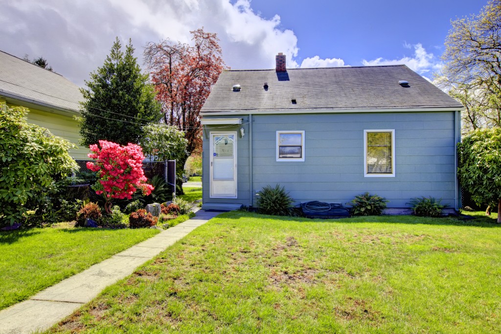 Blue small house with spring landscape from backyard with green grass