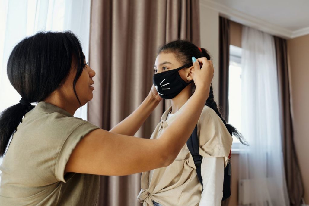 mother putting facemask on her daughter