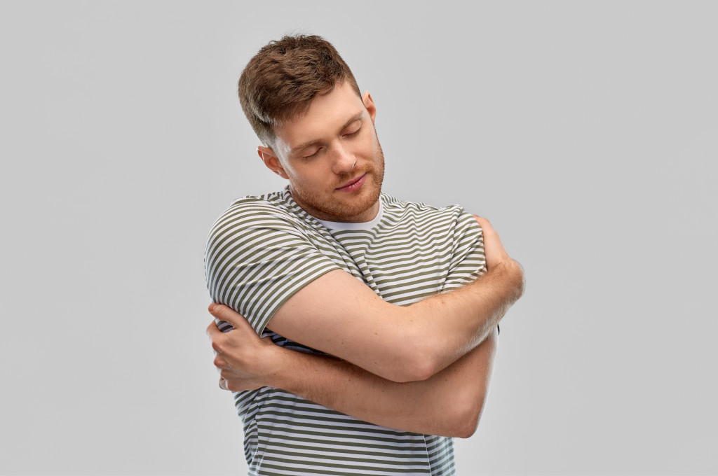 happy young man in striped t-shirt hugging himself